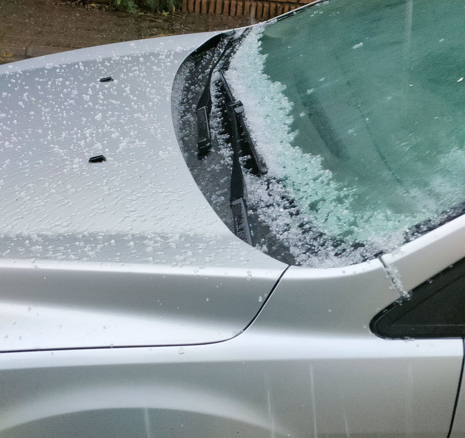 Granizo acumulado en el parabrisas de un coche.