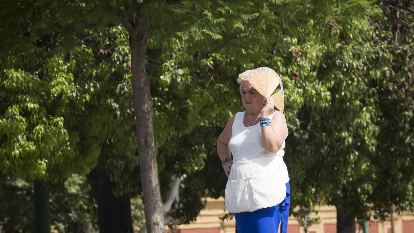 Una mujer se protege del sol con un abanico