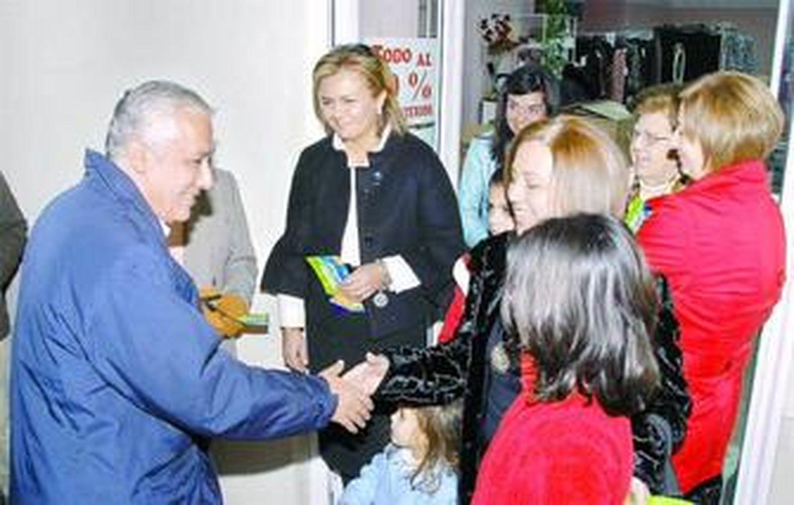 Javier Arenas saluda en Cabra a un grupo de vecinos a las puertas de un comercio.