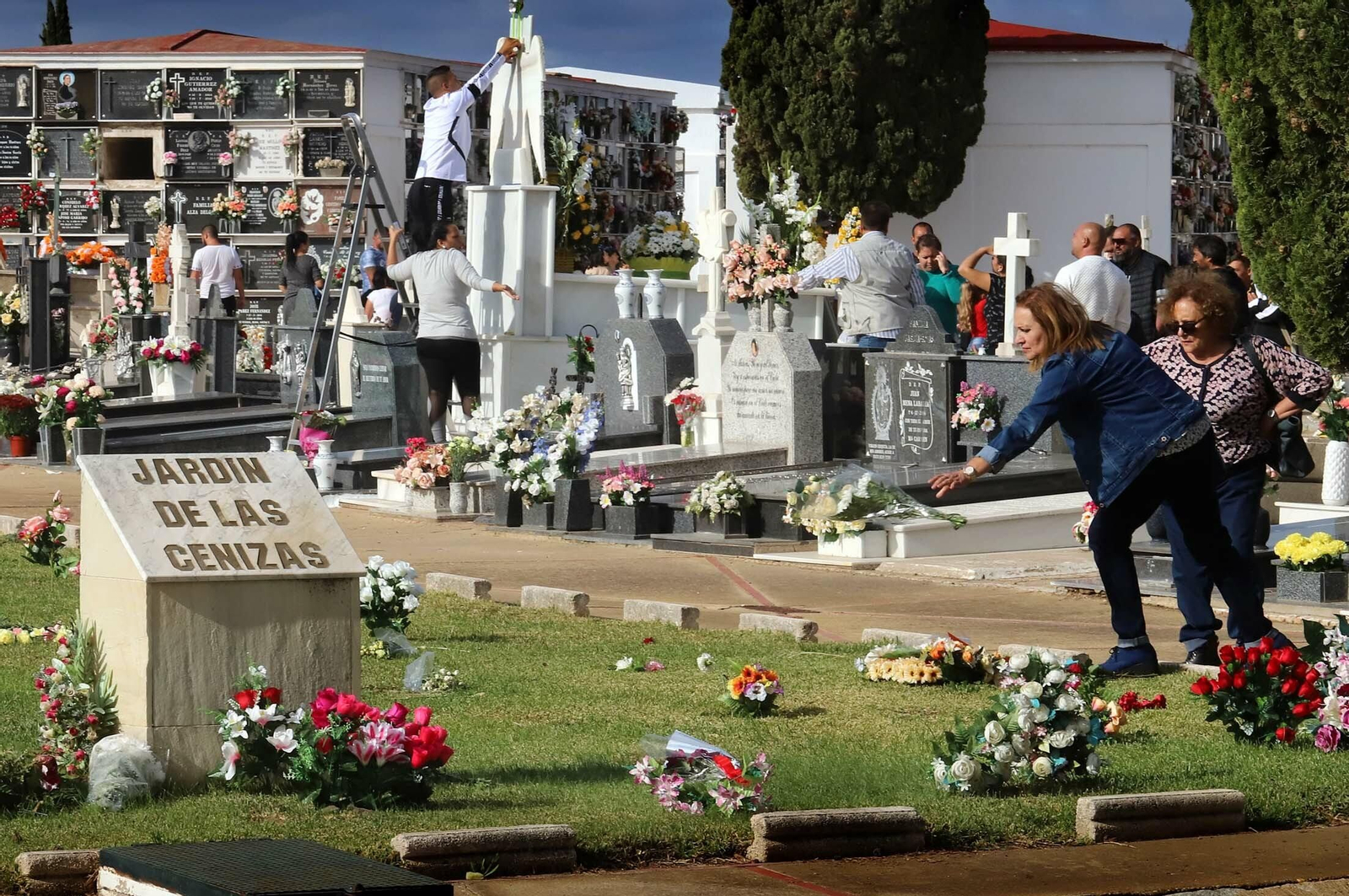 Una mujer tira un ramo de flores al jardín de las cenizas.