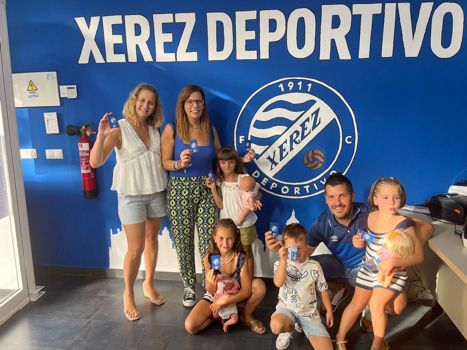 Un grupo de aficionados del Xerez DFC posan con sus carnés en la oficina del club.