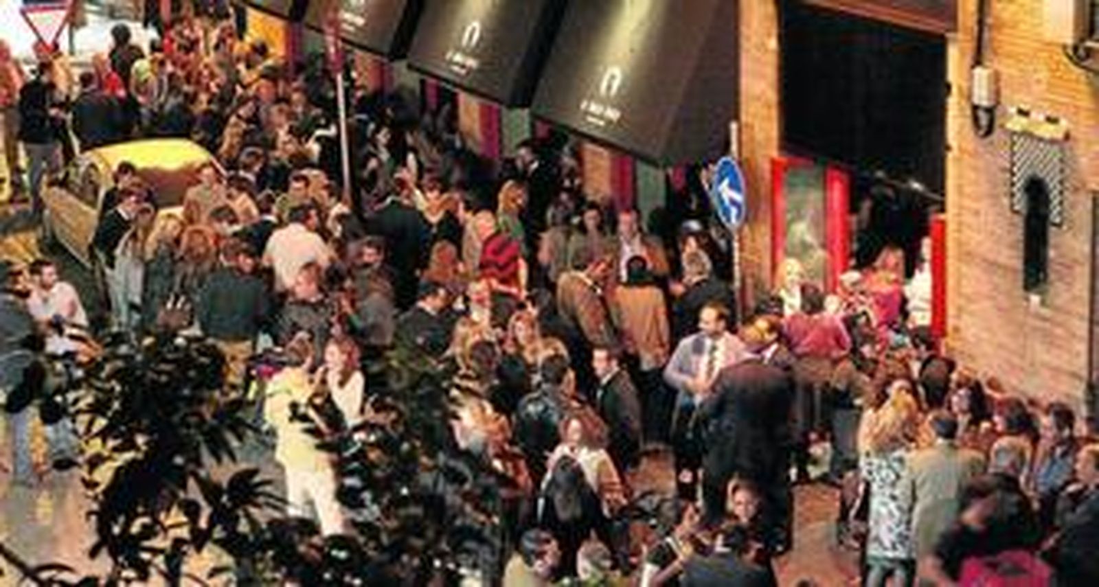 Numerosas personas abarrotan la puerta de un establecimiento.