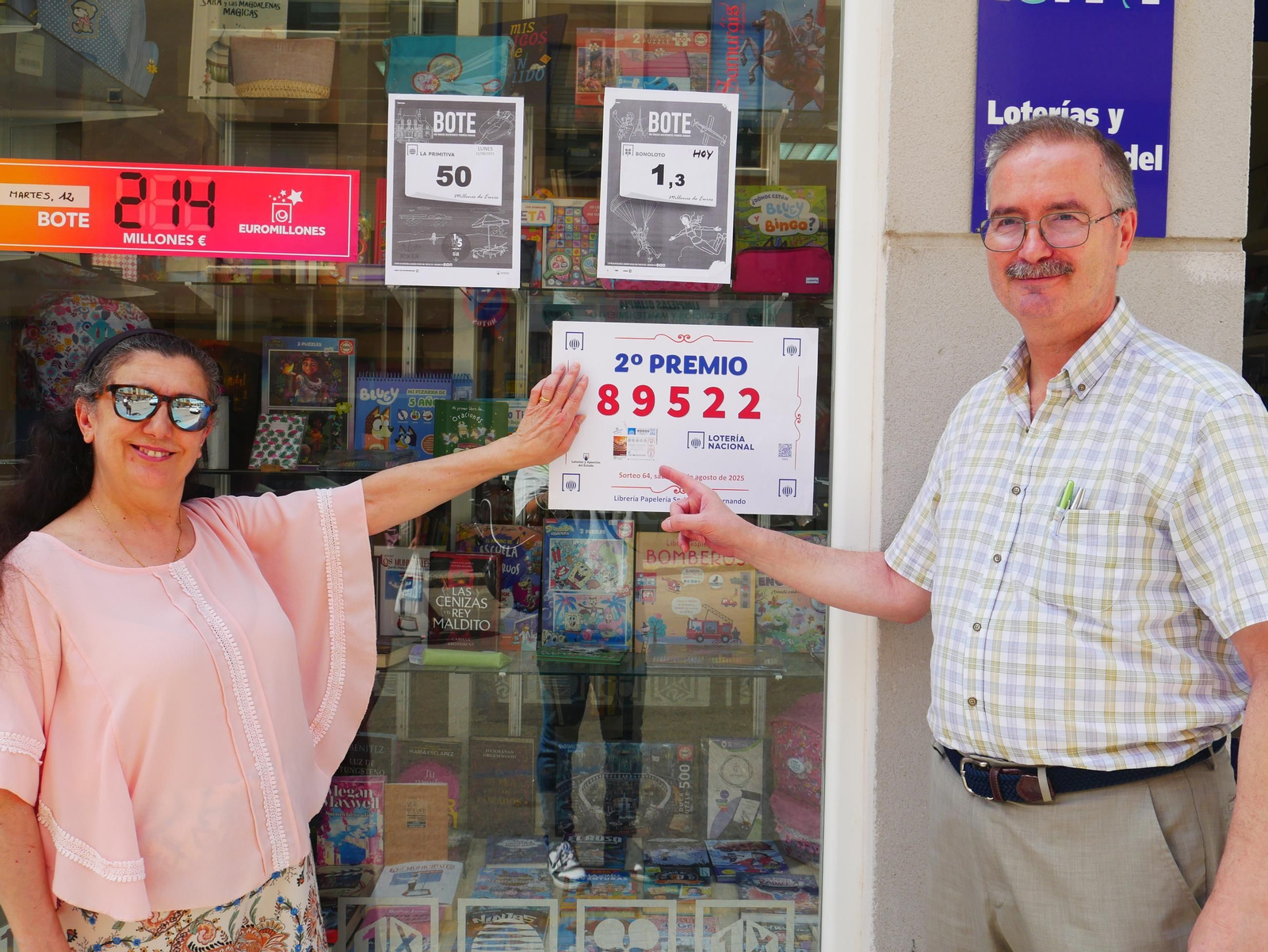 Los gerentes de esta administración de Lotería, junto al cartel del último premio entregado.