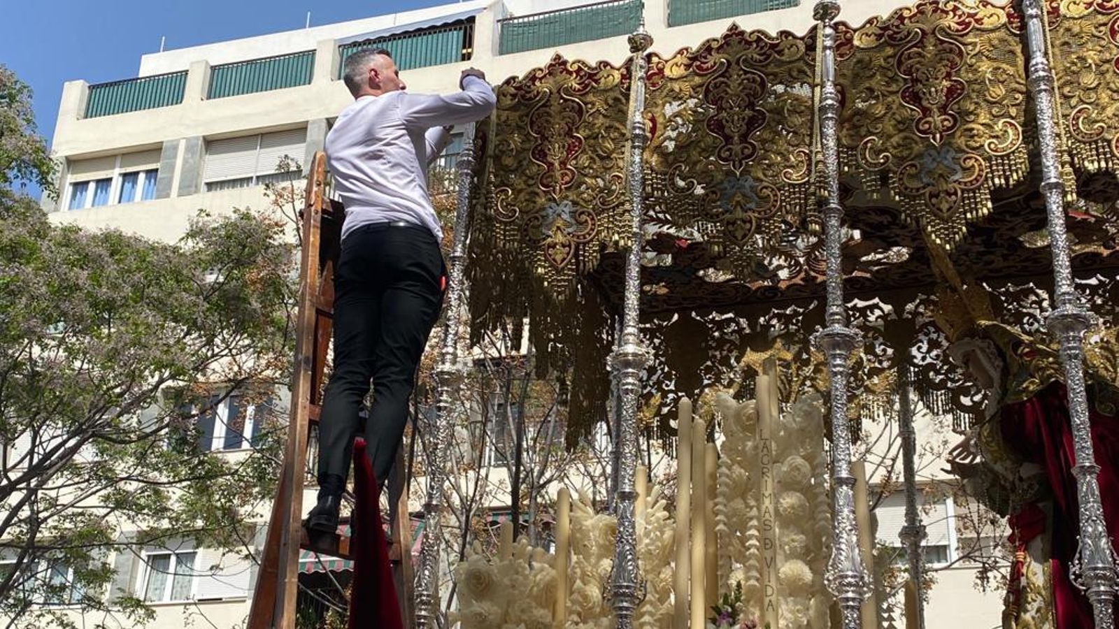 Un hermano de Borriquita arregla un desperfecto en el palio de Amparo.