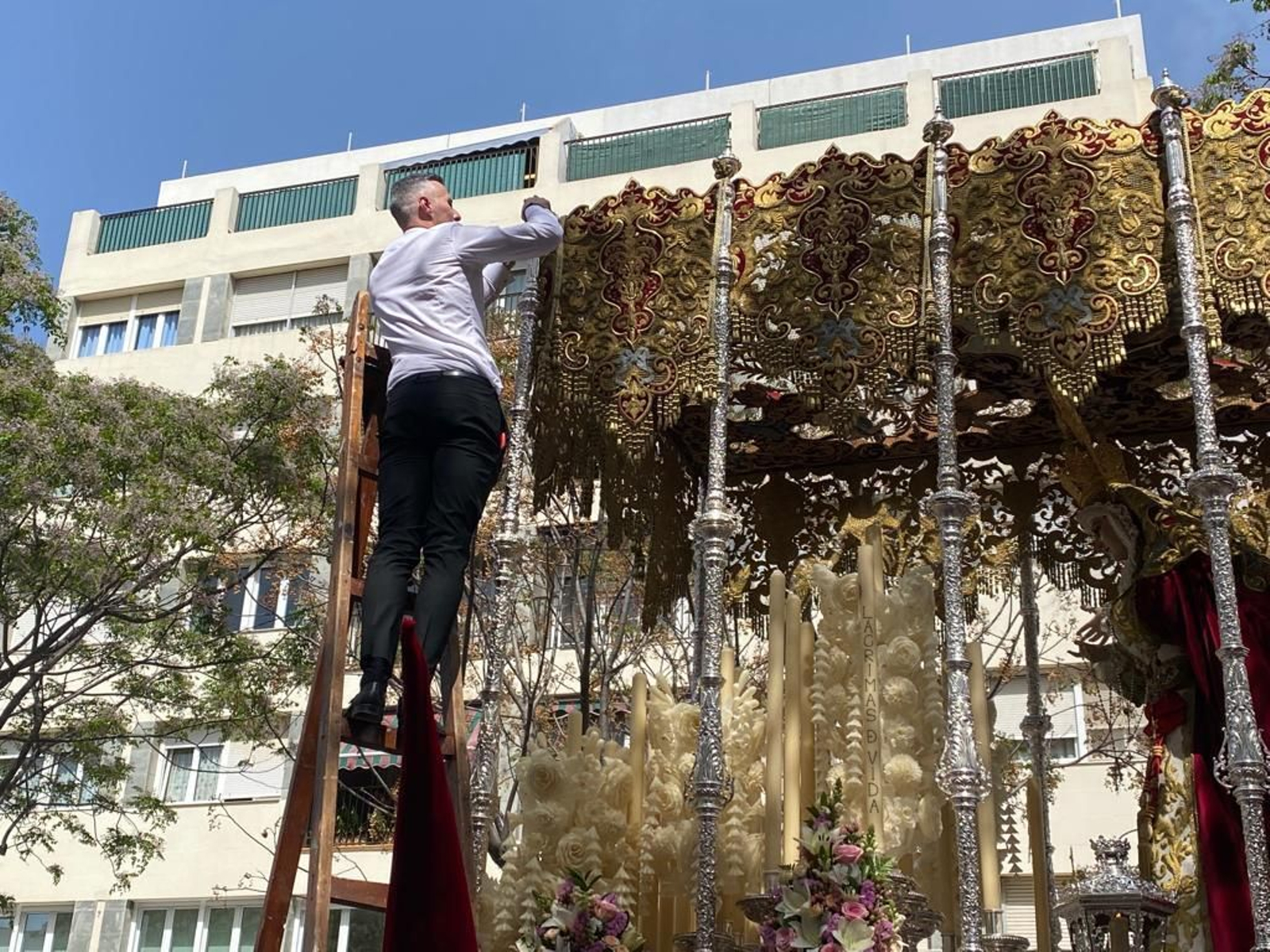Un hermano de Borriquita arregla un desperfecto en el palio de Amparo.