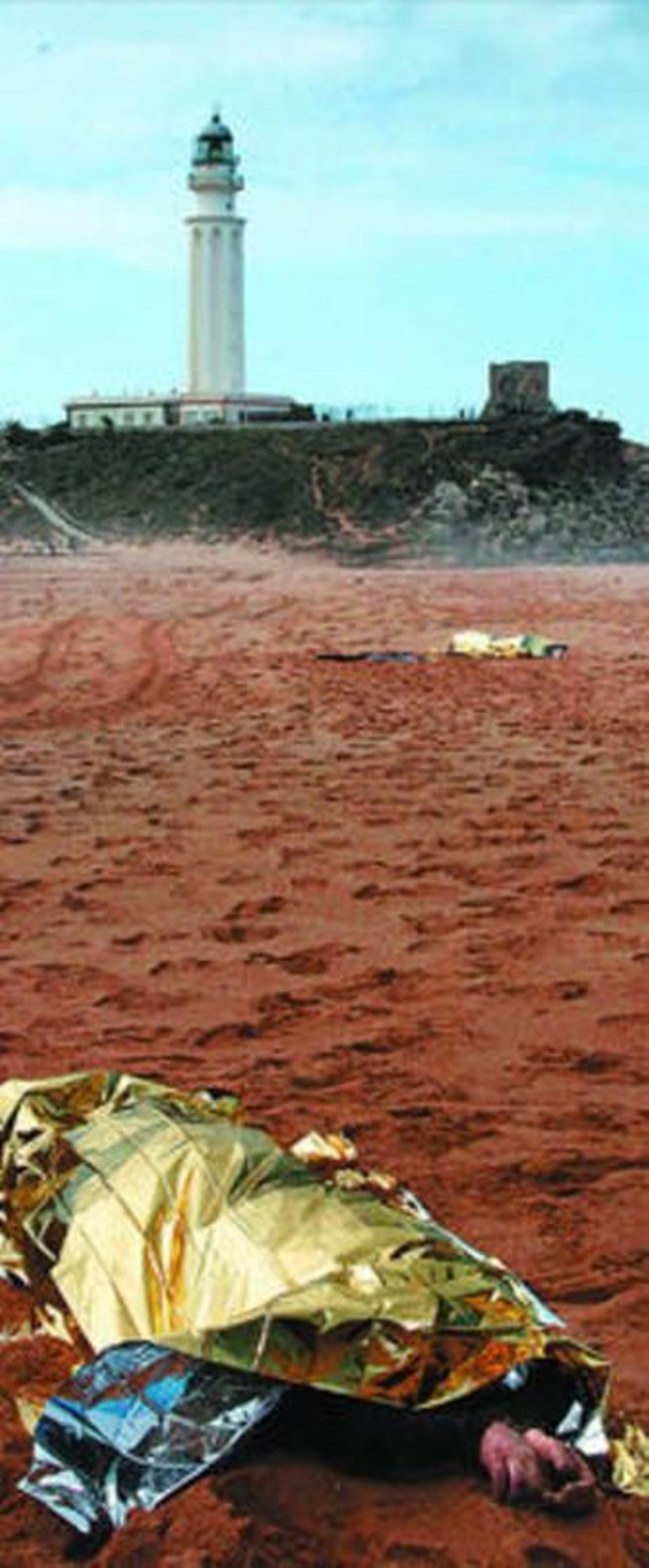 El cuerpo de dos de los fallecidos, con el faro de Trafalgar al fondo.