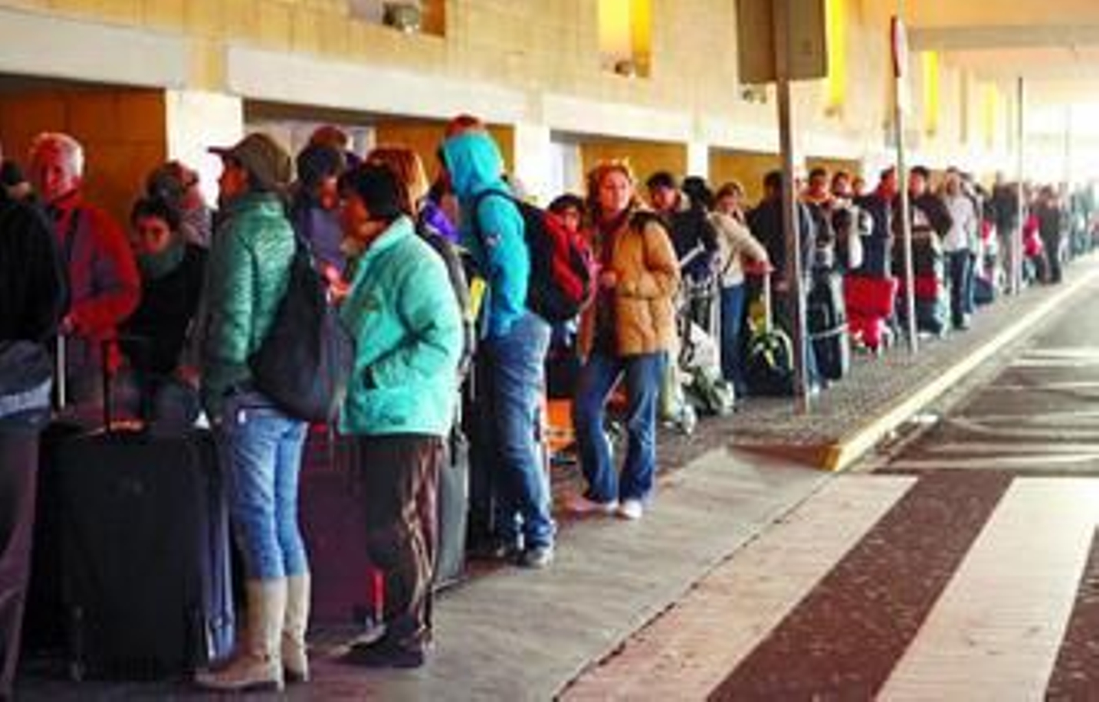 Pasajeros derivados a Sevilla por el cierre de Madrid esperan un autobús.