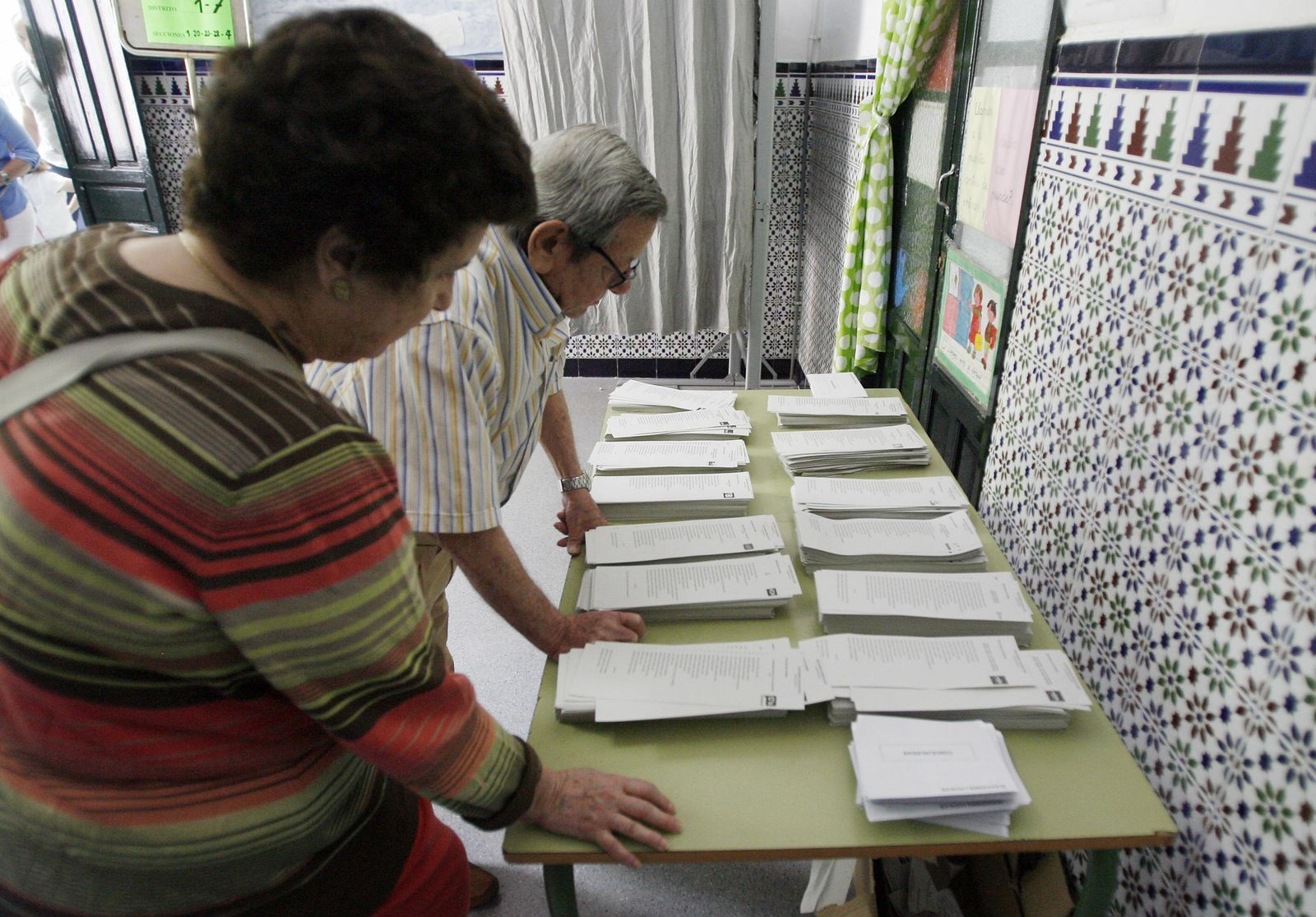 Dos electores mientras cogen sus papeleta en un colegio electoral.