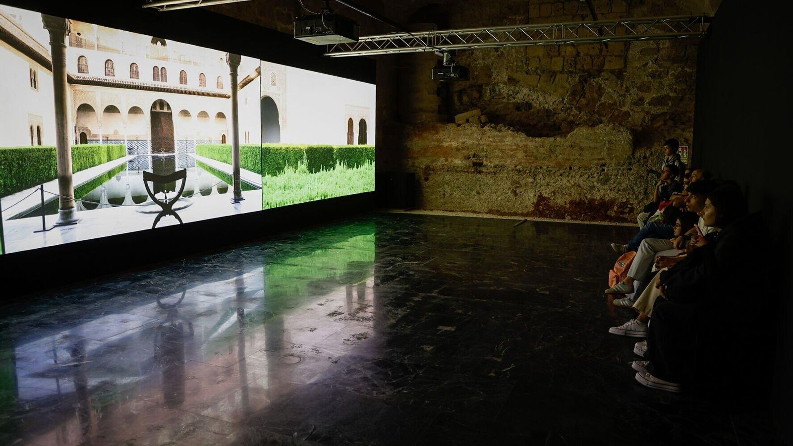 Un grupo de visitantes contempla el audiovisual de la muestra.