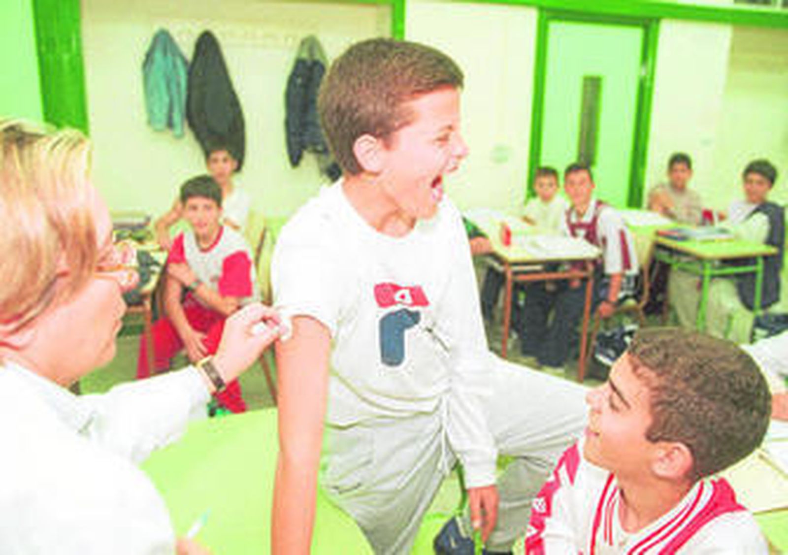 Vacunan a un niño en su centro escolar.