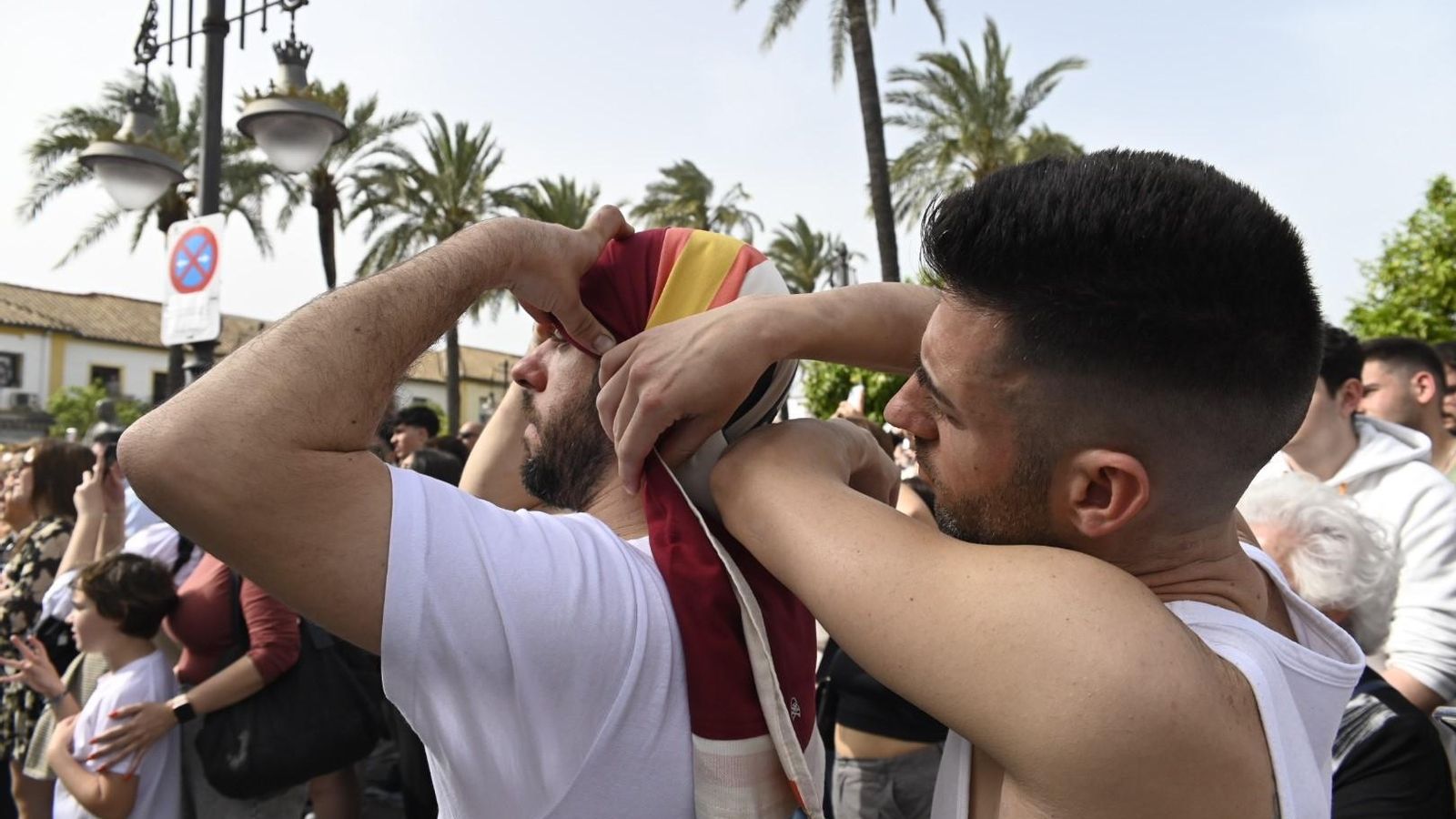 Dos costaleros se ayudan a colocarse el costal.