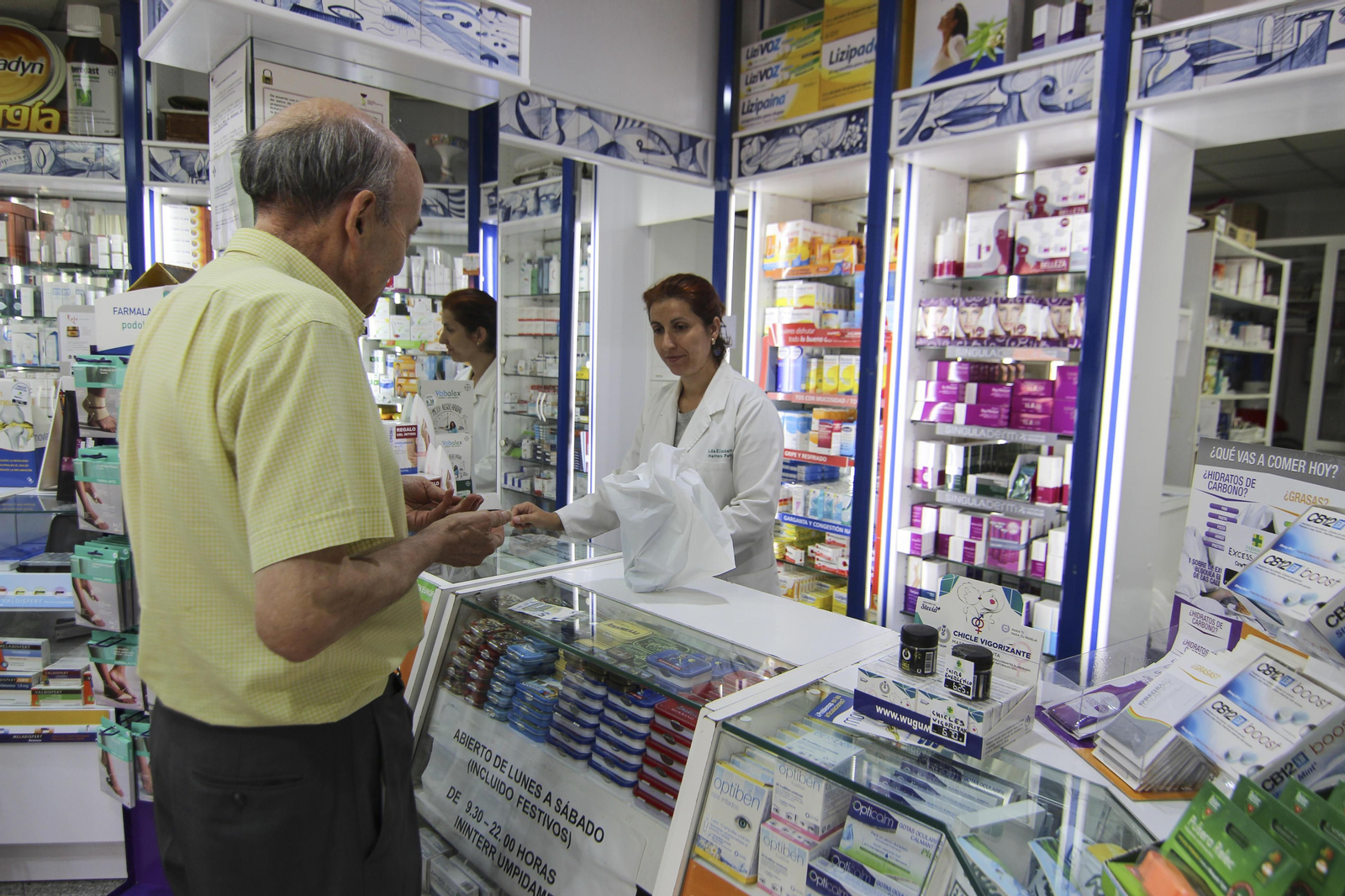 Una farmacéutica atiende a un pensionista.