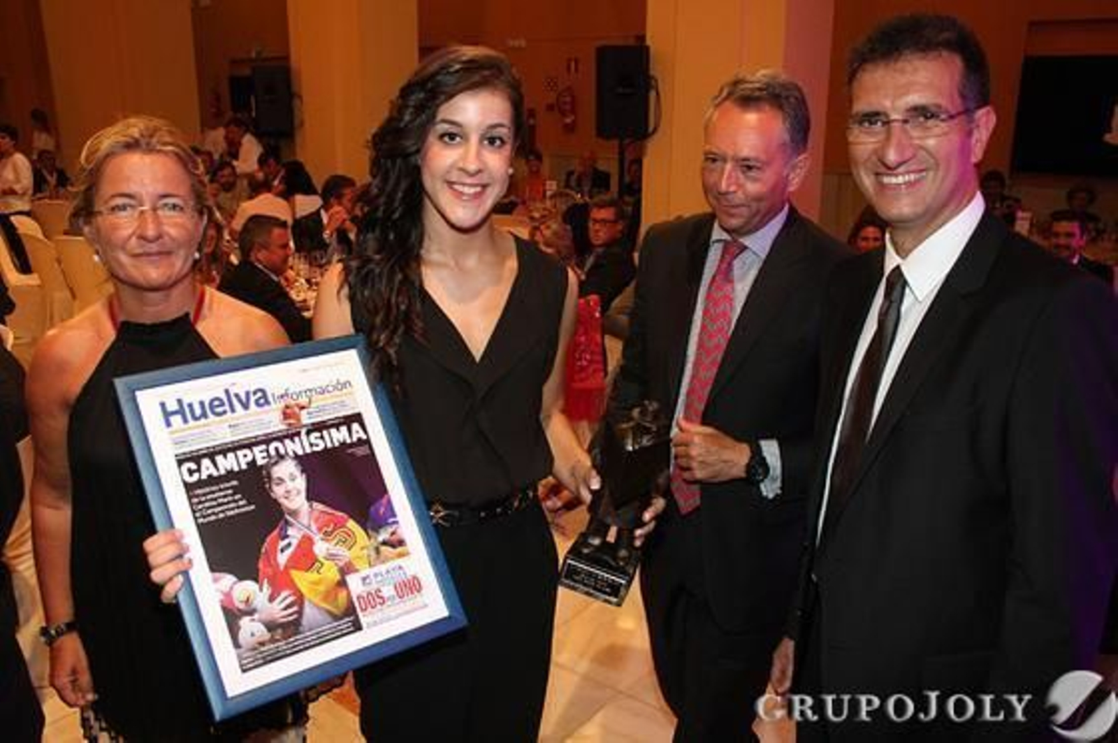 Adelaida Mellado, José Joly y Javier Chaparro entregaron a Carolina Marín la portada de 'Huelva Información' con la noticia de su victoria en Dinamarca.

Foto: Alberto Dominguez/ Paqui Segarra