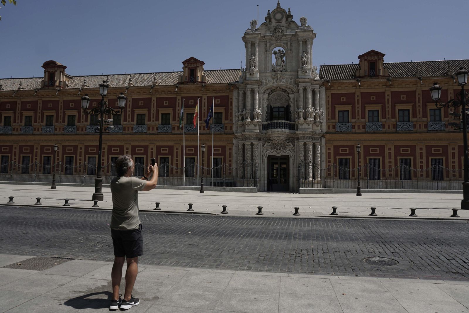 Un viandante fotografía la monumental fachada barroca del Palacio de San Telmo, actual sede del Gobierno andaluz.