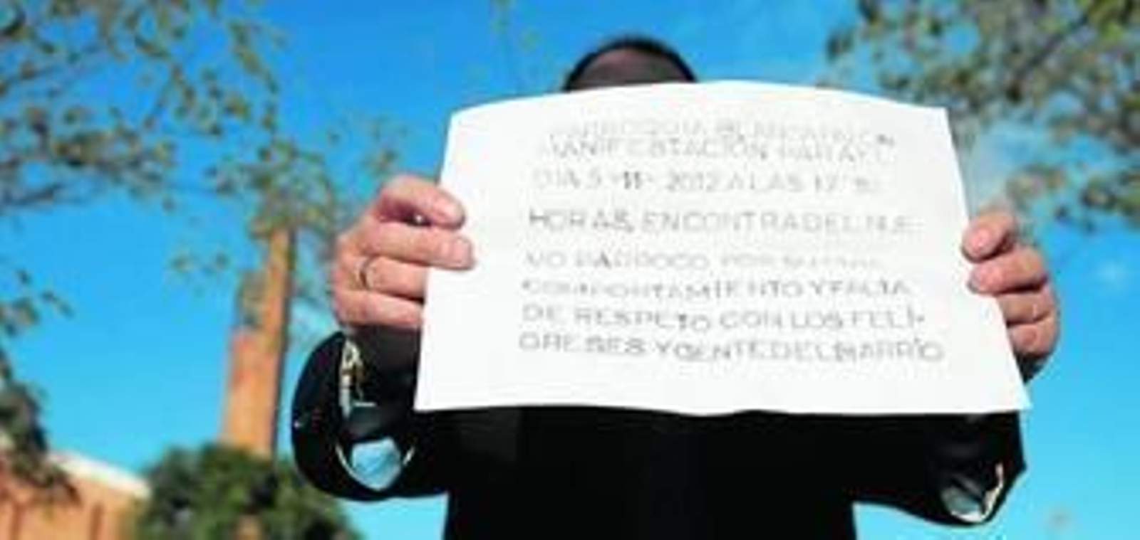 Un vecino muestra uno de los carteles colocados en el barrio para convocar la protesta del próximo 5 de noviembre.