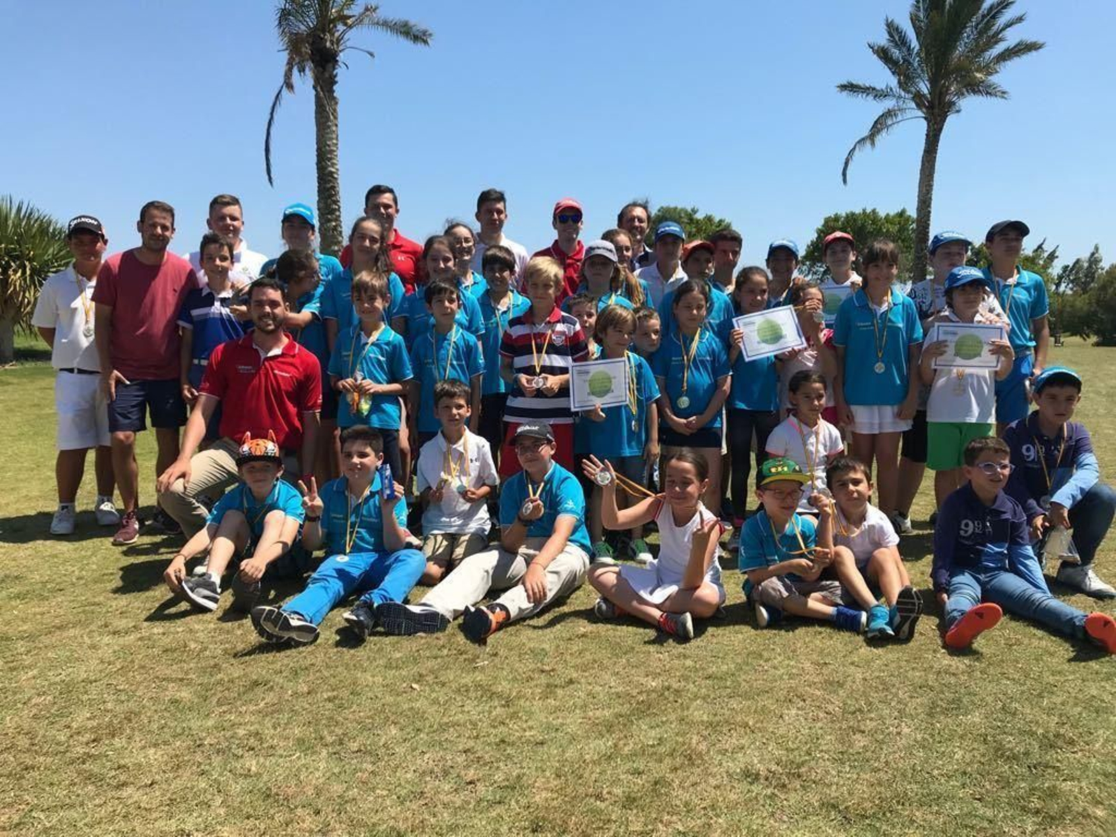 Los niños posan con sus medallas en el campo de golf.
