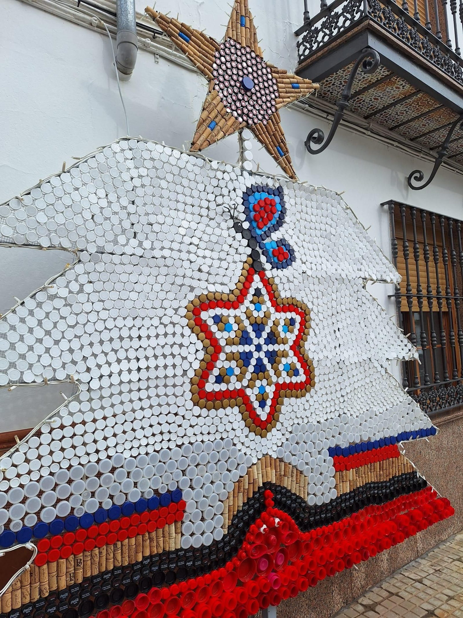 Una estrella corona un árbol de Navidad hecho de material reciclado.