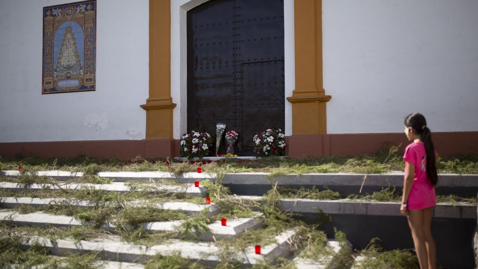 Una niña contempla la alfombra de romeros que cubren los siete escalones que suben las hermandades al pasar por Villamanrique.