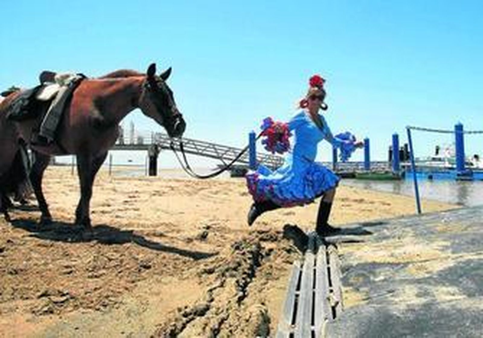 Una rociera tira de su caballo para acceder a una barcaza en la playa de Bajo de Guía, en Sanlúcar, en la romería de 2010.