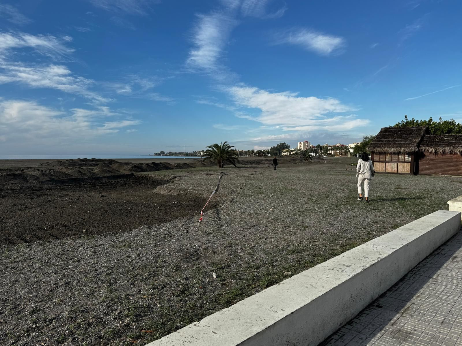 Una persona camina por la Playa del Cable con el cielo despejado pese al aviso amarillo por lluvia