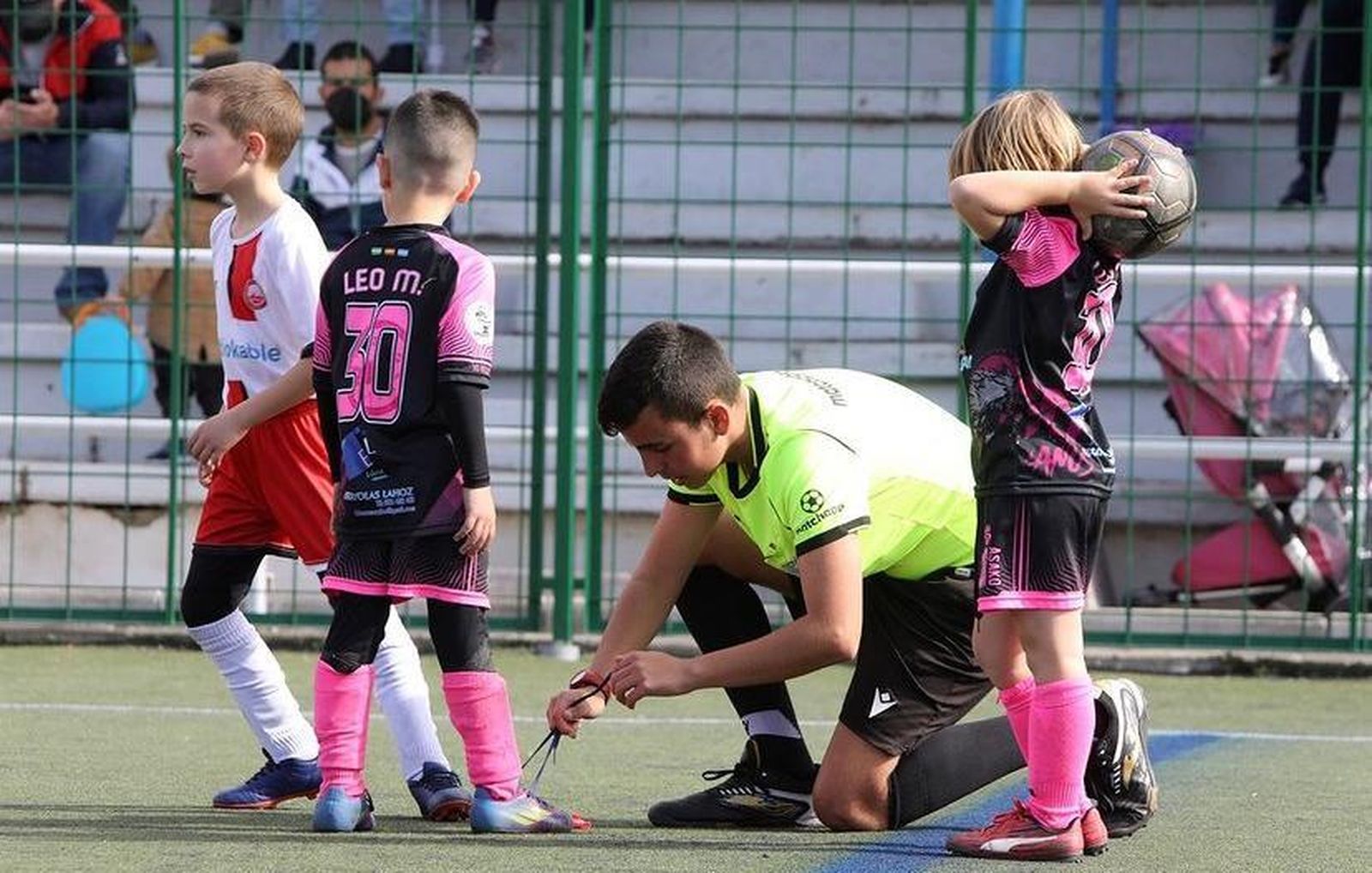 Izan Barbero, el joven árbitro de Granada, ata los cordones a uno de los jugadores.