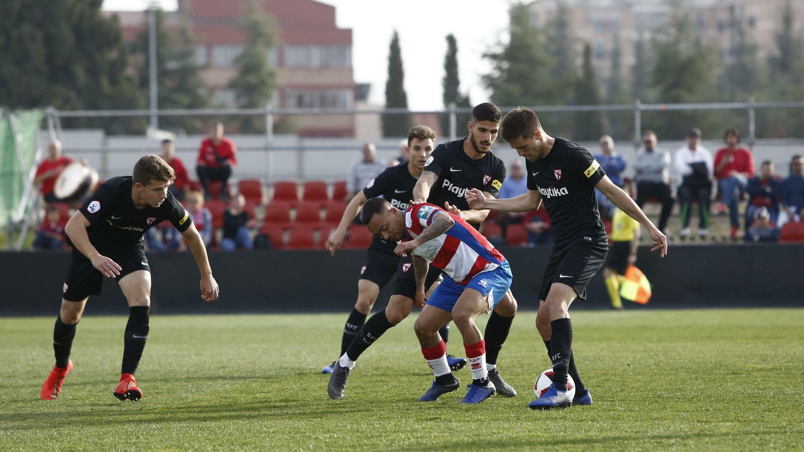 Juancho pierde el balón rodeado por lo jugadores sevillistas Genaro y Berrocal.