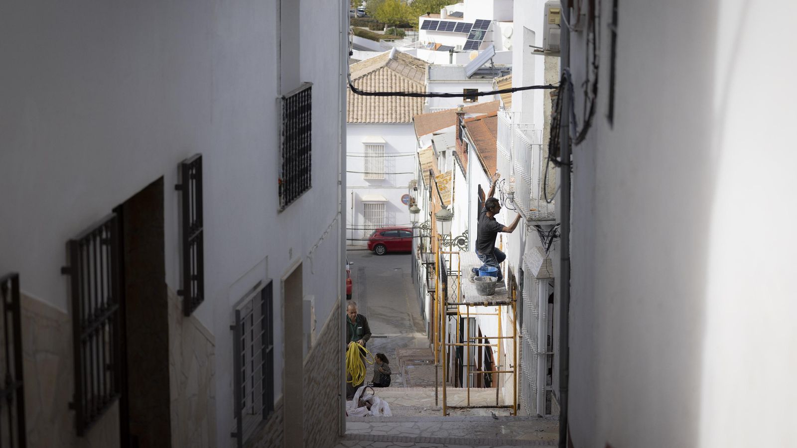 Un hombre trabaja en la fachada de una casa de Pruna.