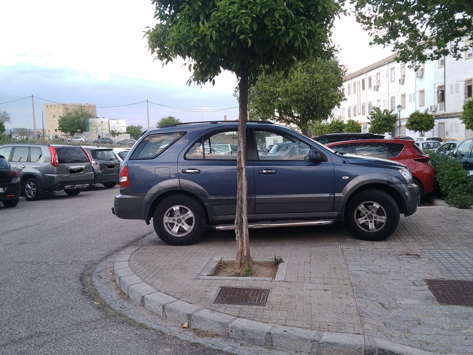 Coches aparcados en la acera en el Campo de la Verdad.