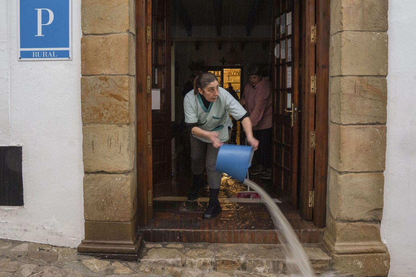 Varias personas achican agua de un establecimiento hotelero.