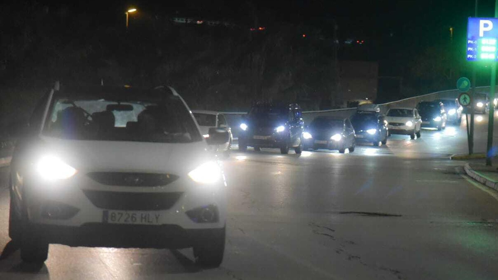 Hilera de coches tras abandonar el aparcamiento del centro comercial.