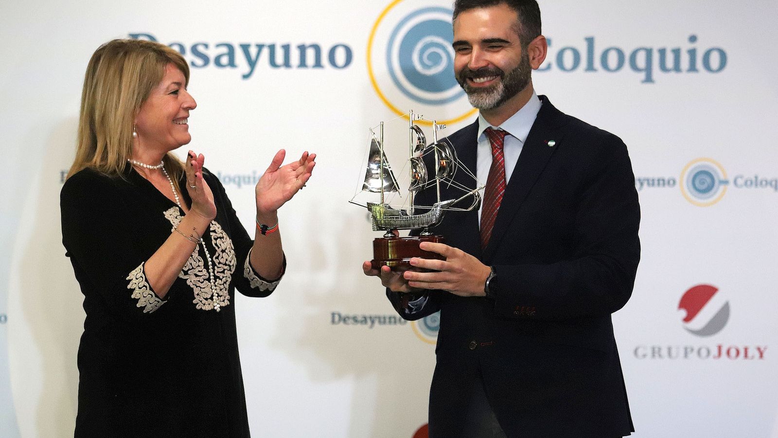 Pilar Miranda entrega al consejero Ramón Fernández-Pacheco una carabela de plata como obsequio.