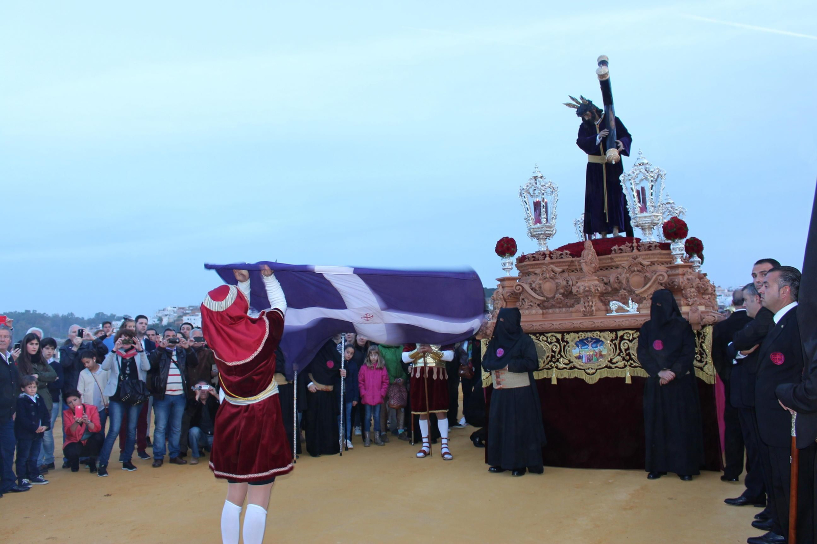 El abanderado revolea la bandera delante del paso de Jesús Nazareno al llegar a la cima del cerro del Calvario.