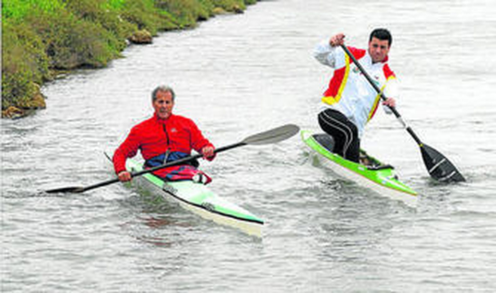 Claudio Hernández (i) y Eduardo Varela, entrenador nacional de piragüismo, durante un entrenamiento en el lago de Las Albinas.