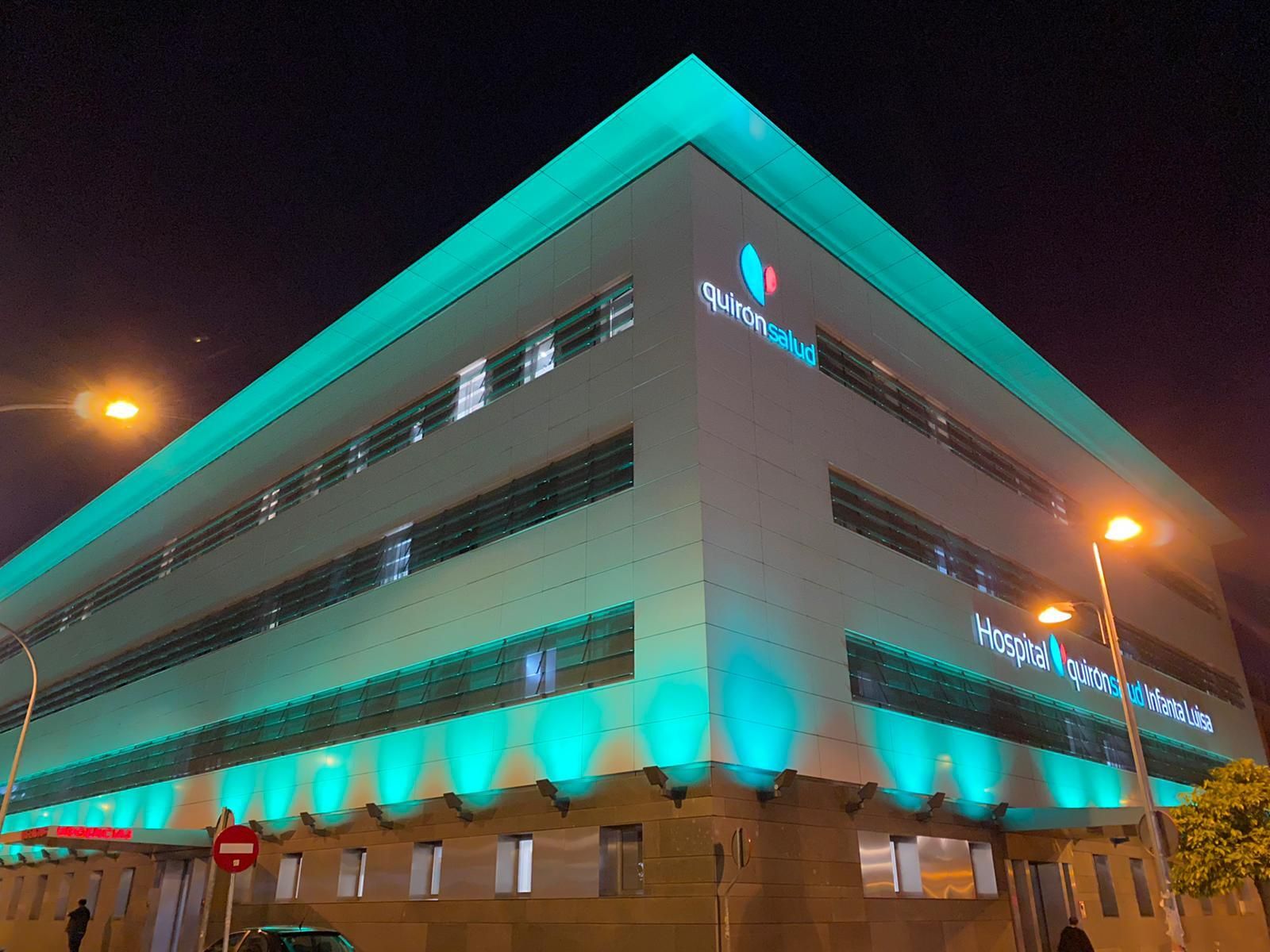 El Hospital Quirónsalud Infanta Luisa con su fachada iluminada de color verde esperanza.
