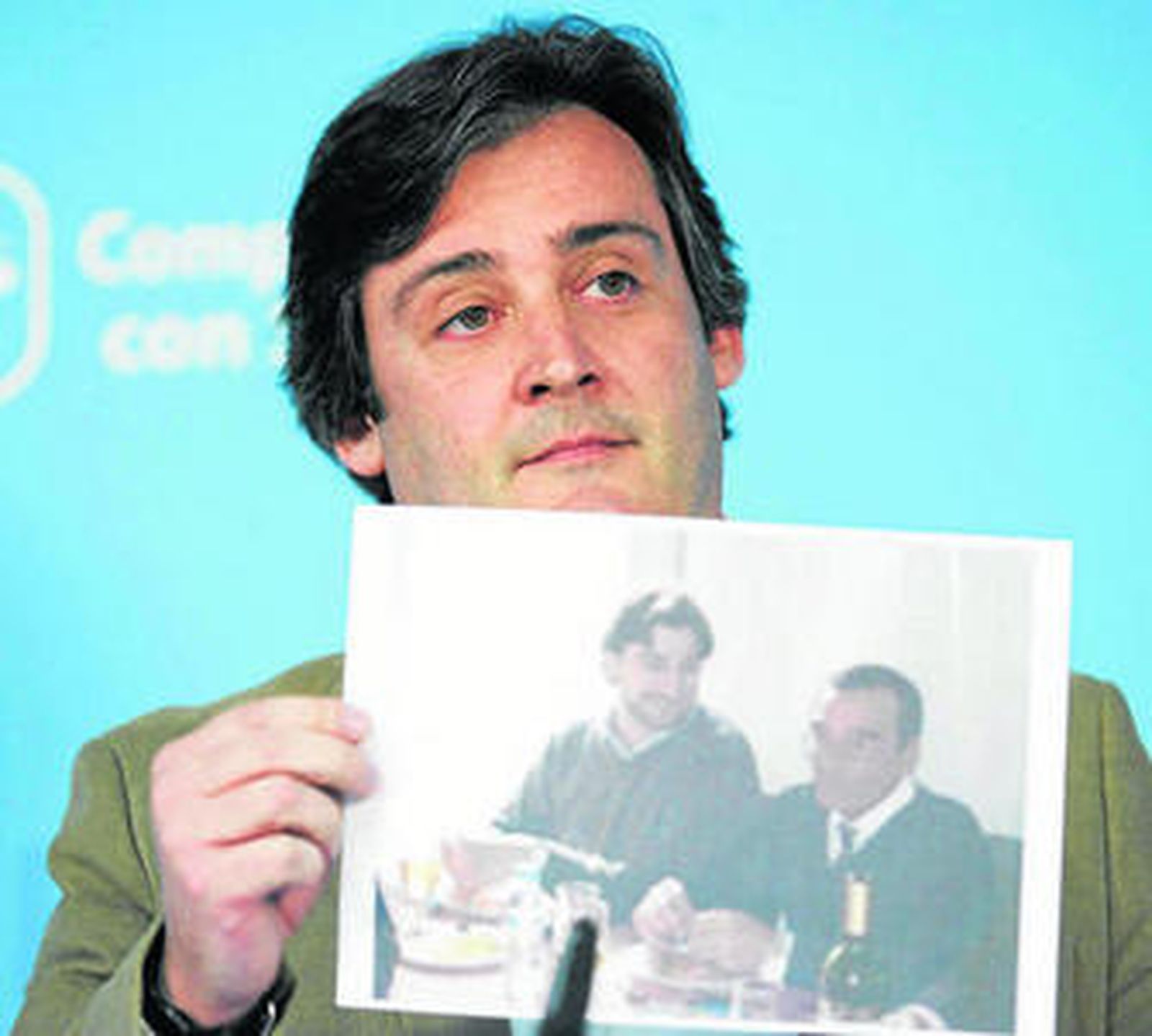 Eloy Carmona muestra una foto del edil andalucista, en la esquina de la mesa, comiendo gambas.