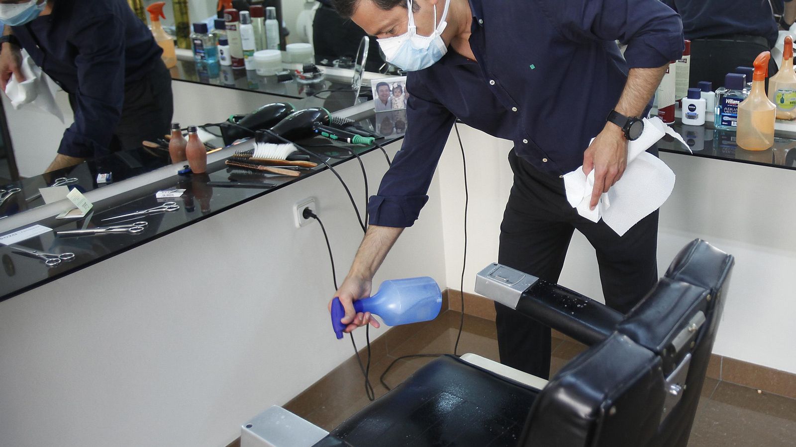 El peluquero Antonio Boza desinfecta el sillón antes de pasar a un nuevo cliente.