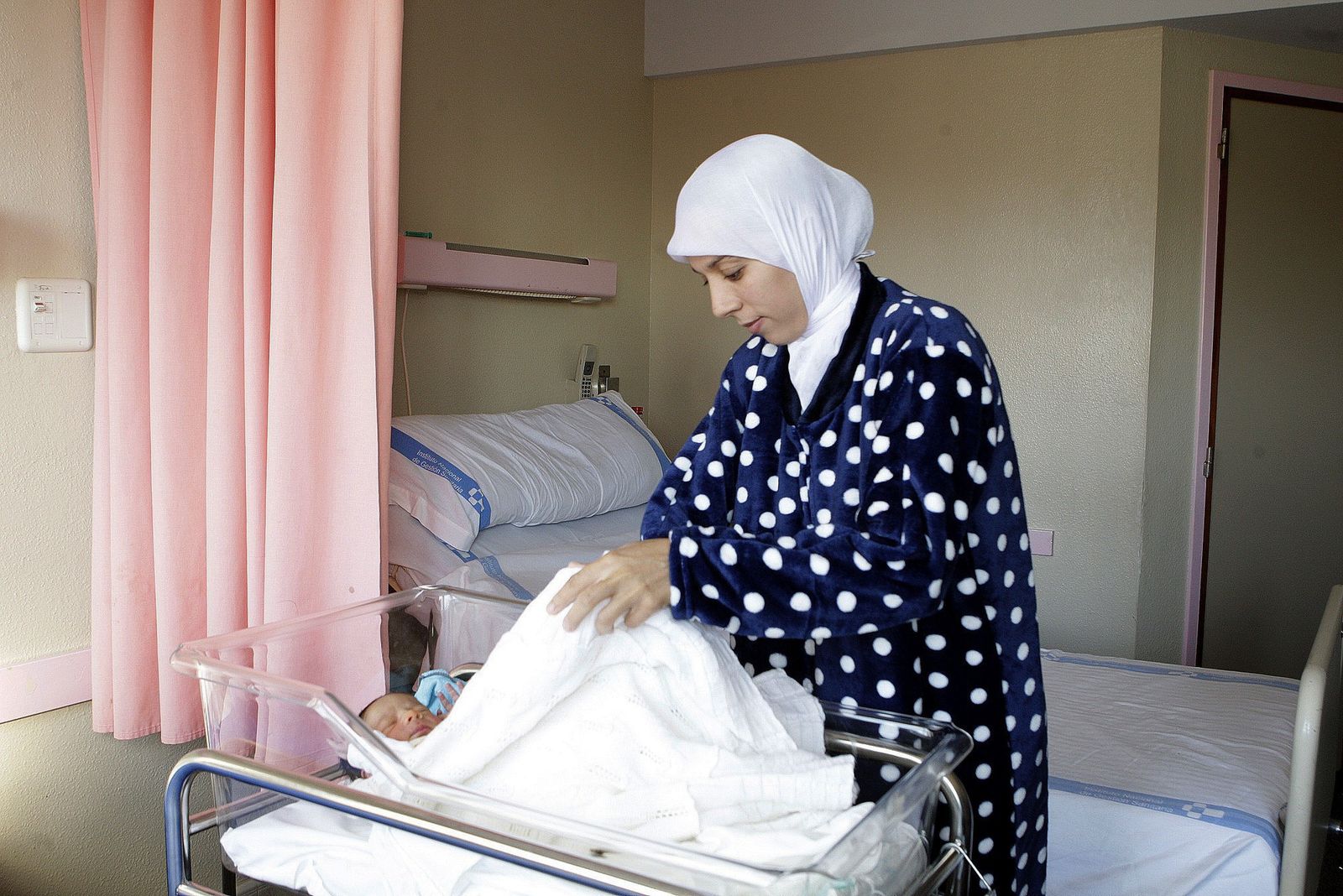 Una mujer de origen extranjero  arropa a su bebé recién nacido, en una fotografía de archivo.