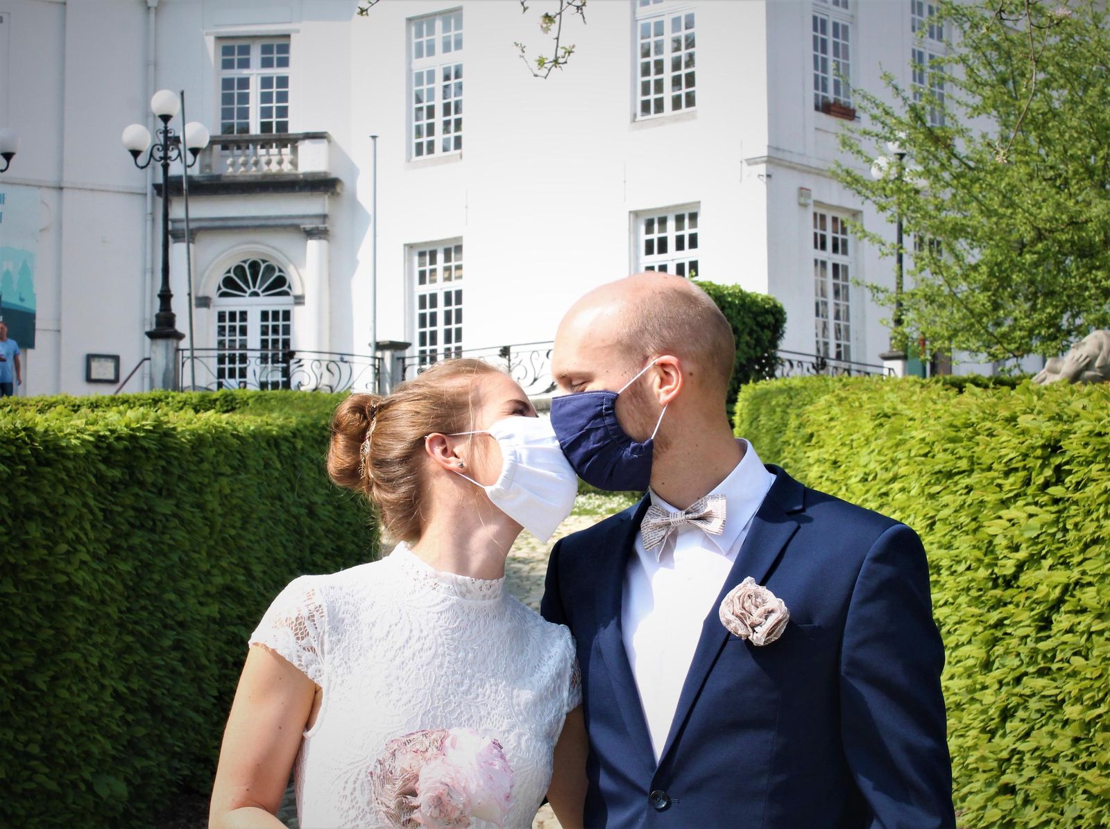 Una pareja de recién casados celebra el momento besándose con mascarillas.