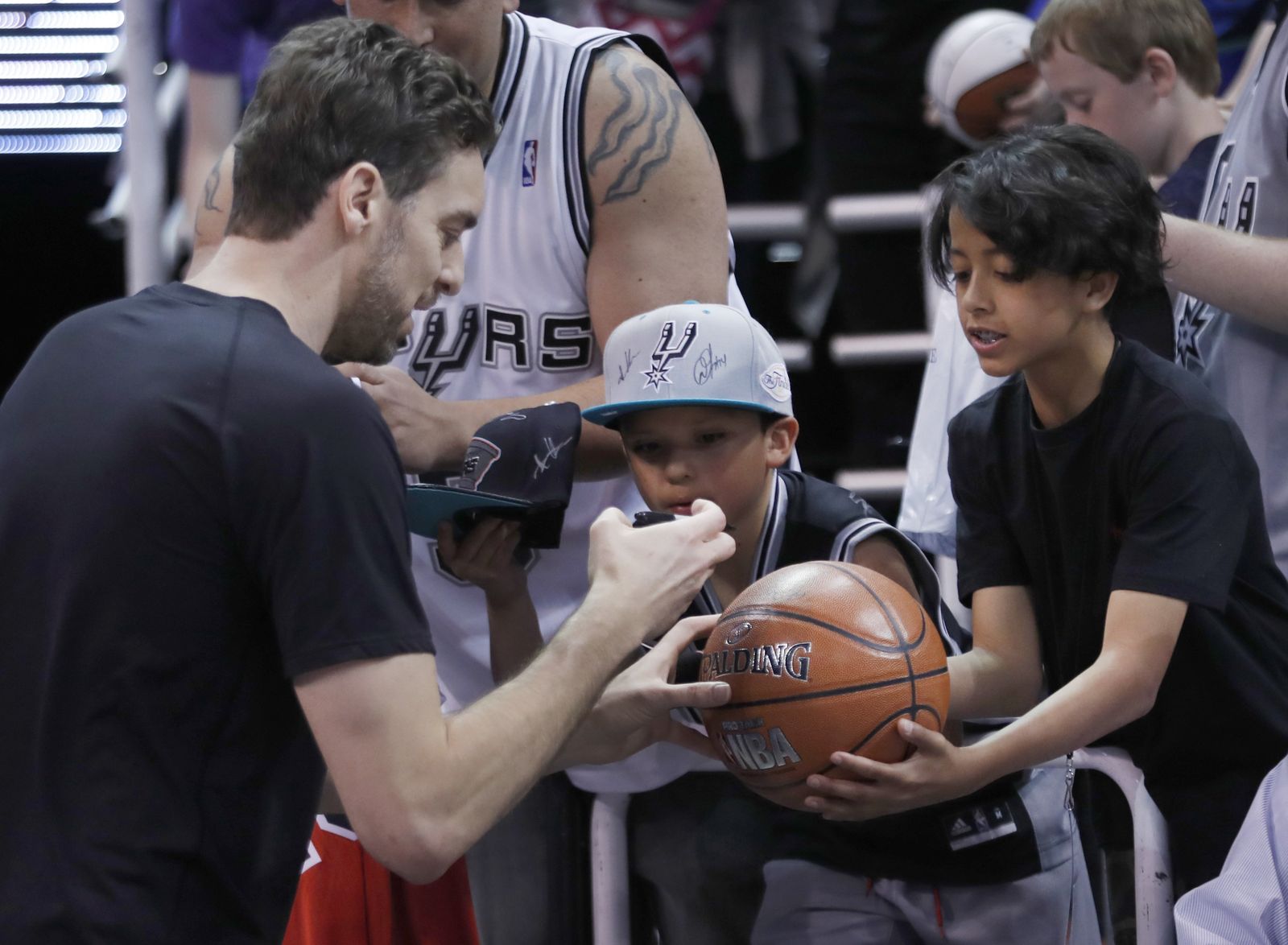 Gasol, firma un balón para un niño antes del partido