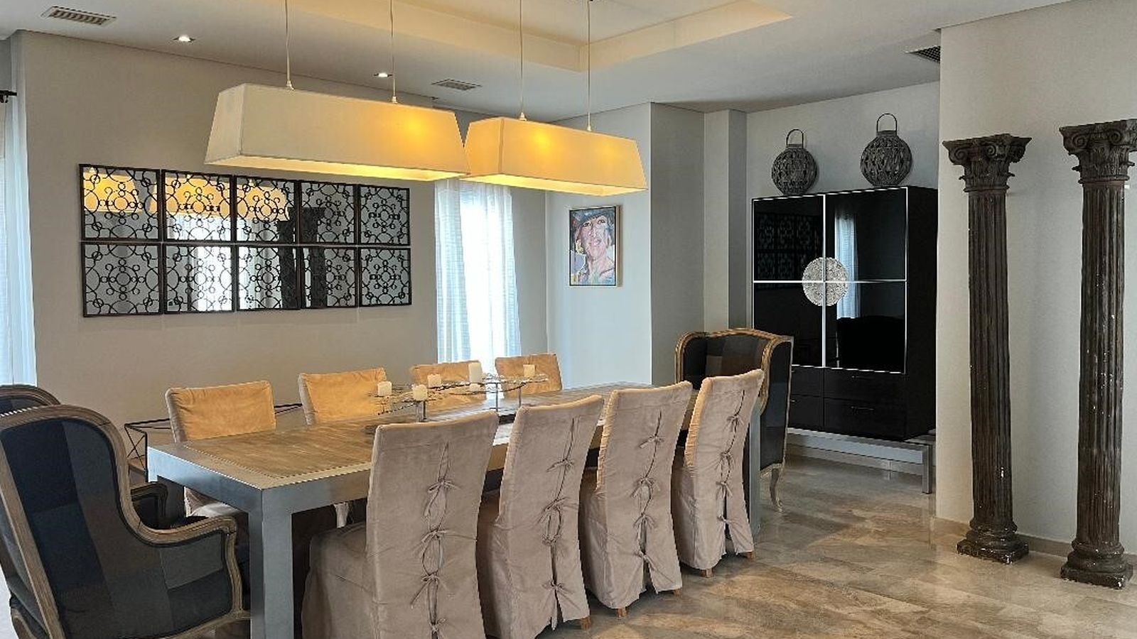 Una imagen del comedor, con una mesa en madera y forja  junto a un conjunto de sillas y pareja de sillones gustavianos.