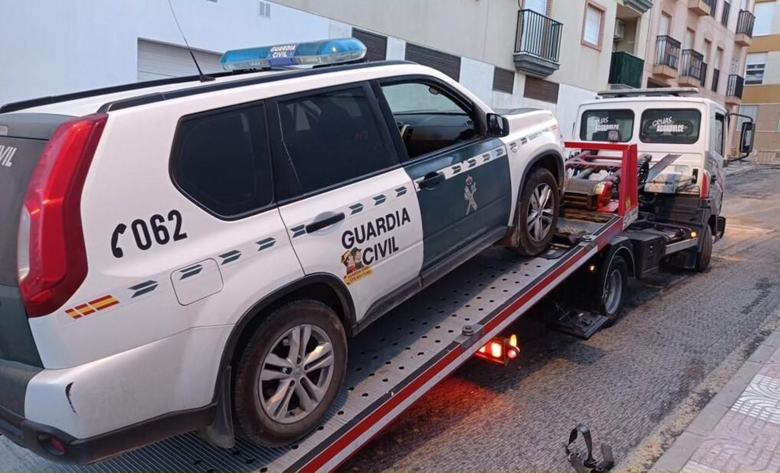 La grúa traslada un patrullero de la Guardia Civil averiado.