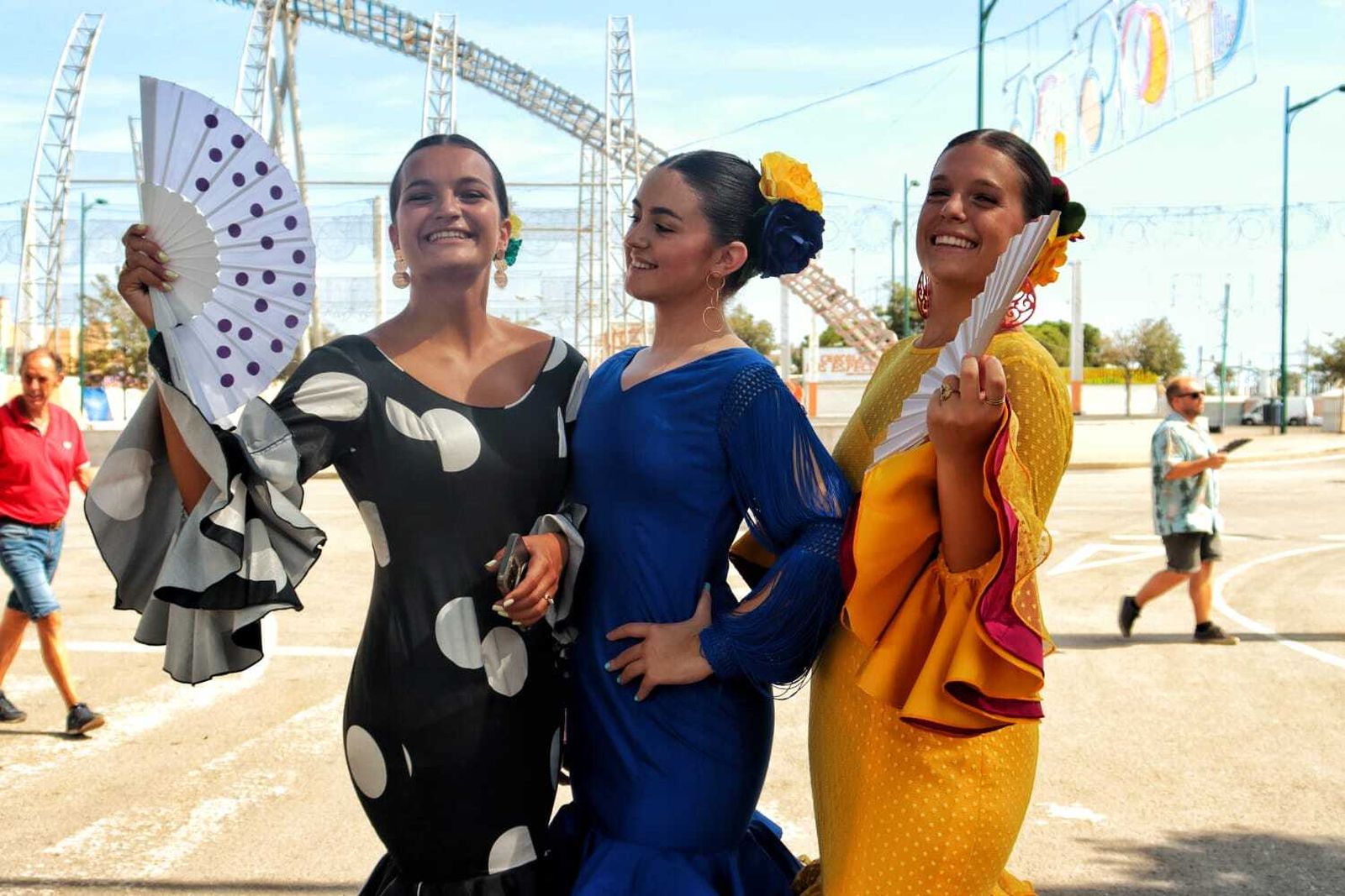 Tres jóvenes con abanicos para mitigar el calor en el Real.
