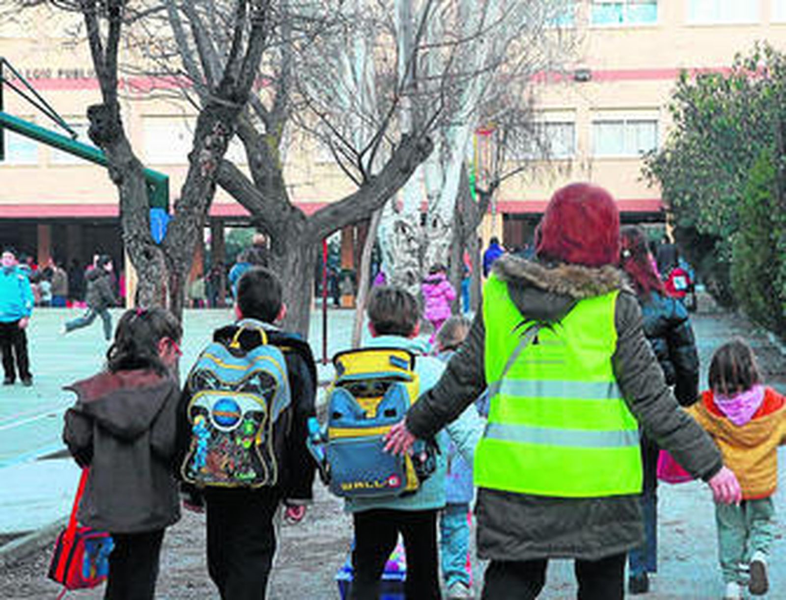 Una mujer facilita el acceso de varios alumnos al colegio Santa Juliana.