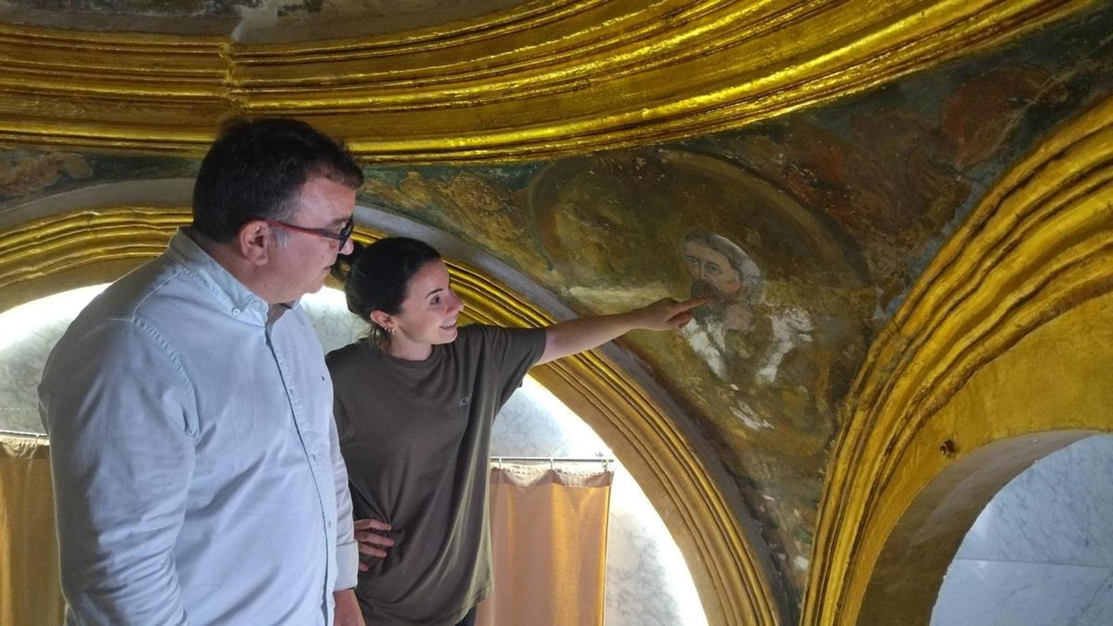 María Trigo junto a una de las pinturas que están restaurando.