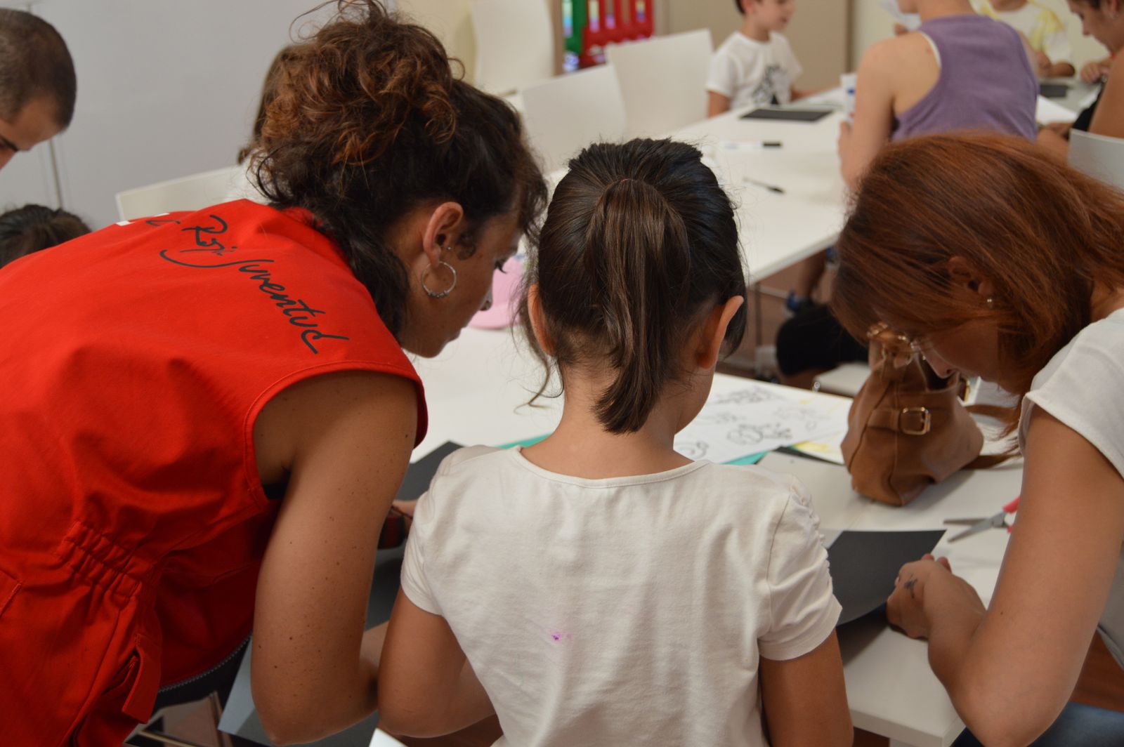 Una voluntaria de Cruz Roja Juventud junto a una familia.