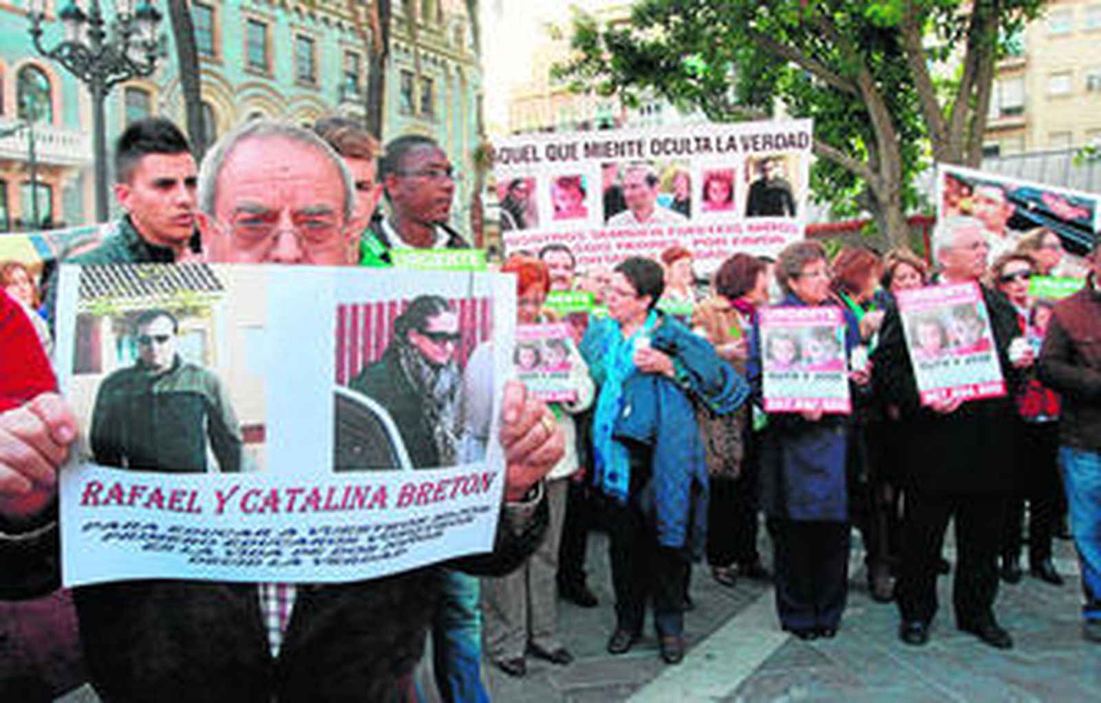 Un hombre porta un cartel con las fotografías y los nombres de los dos hermanos de José Bretón. Al fondo, otra pancarta alude también a la familia paterna de los niños.