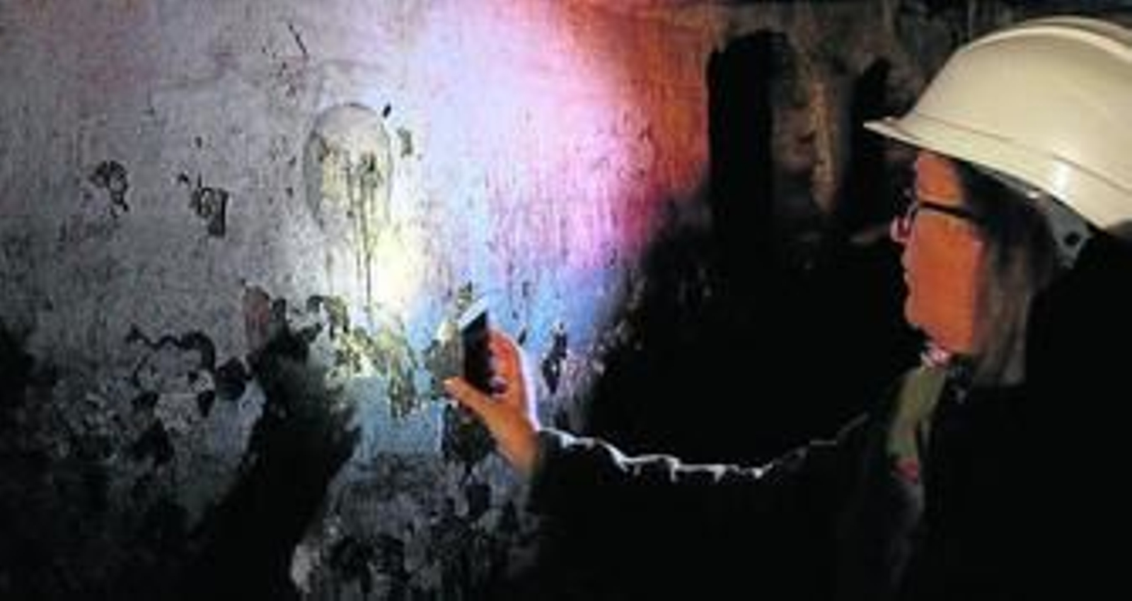 Ana Arancibia alumbra la pintura de una de las calaveras en la cripta de las Ánimas.