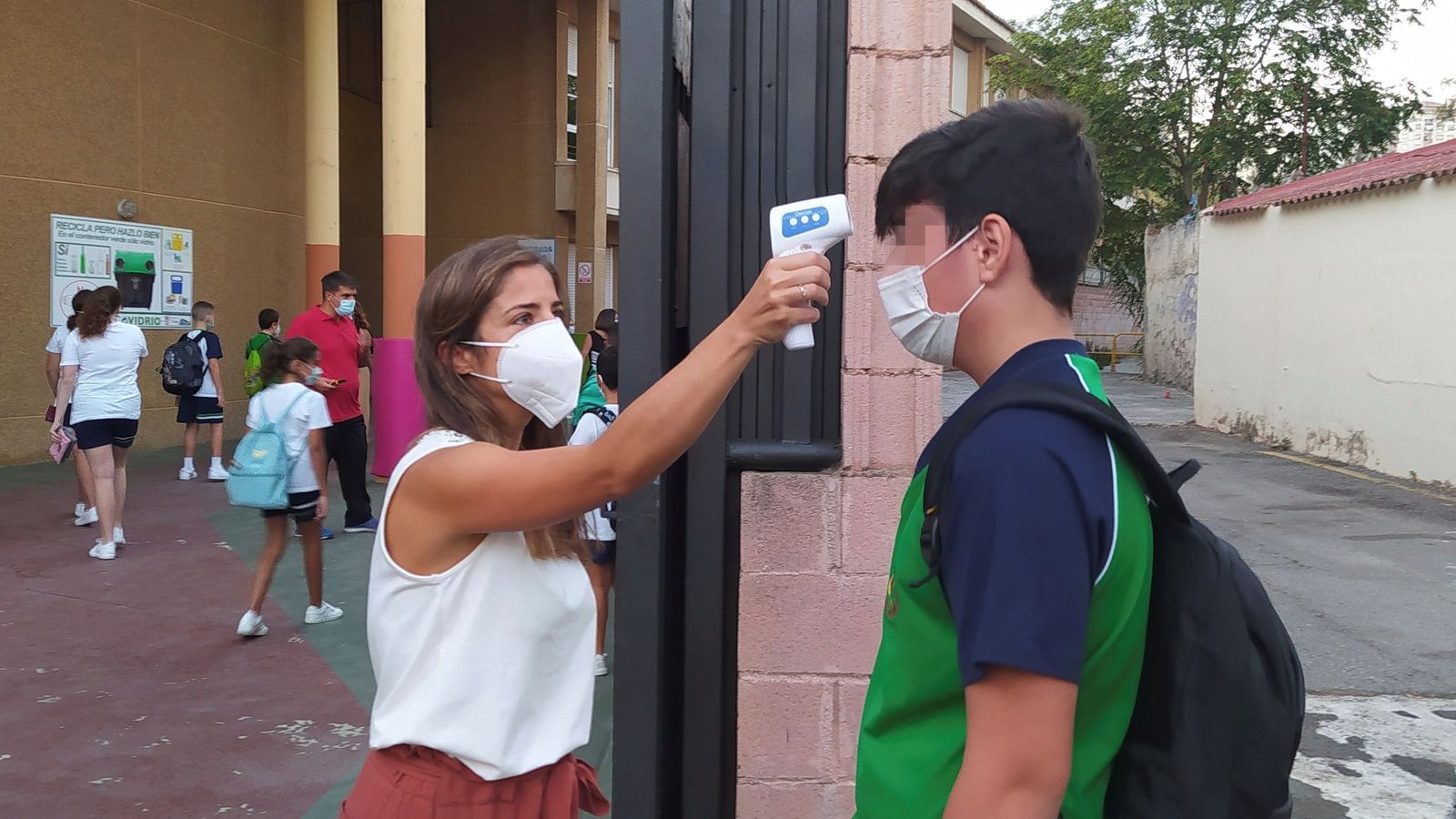Una docente toma la temperatura a un alumno antes de entrar en el centro.
