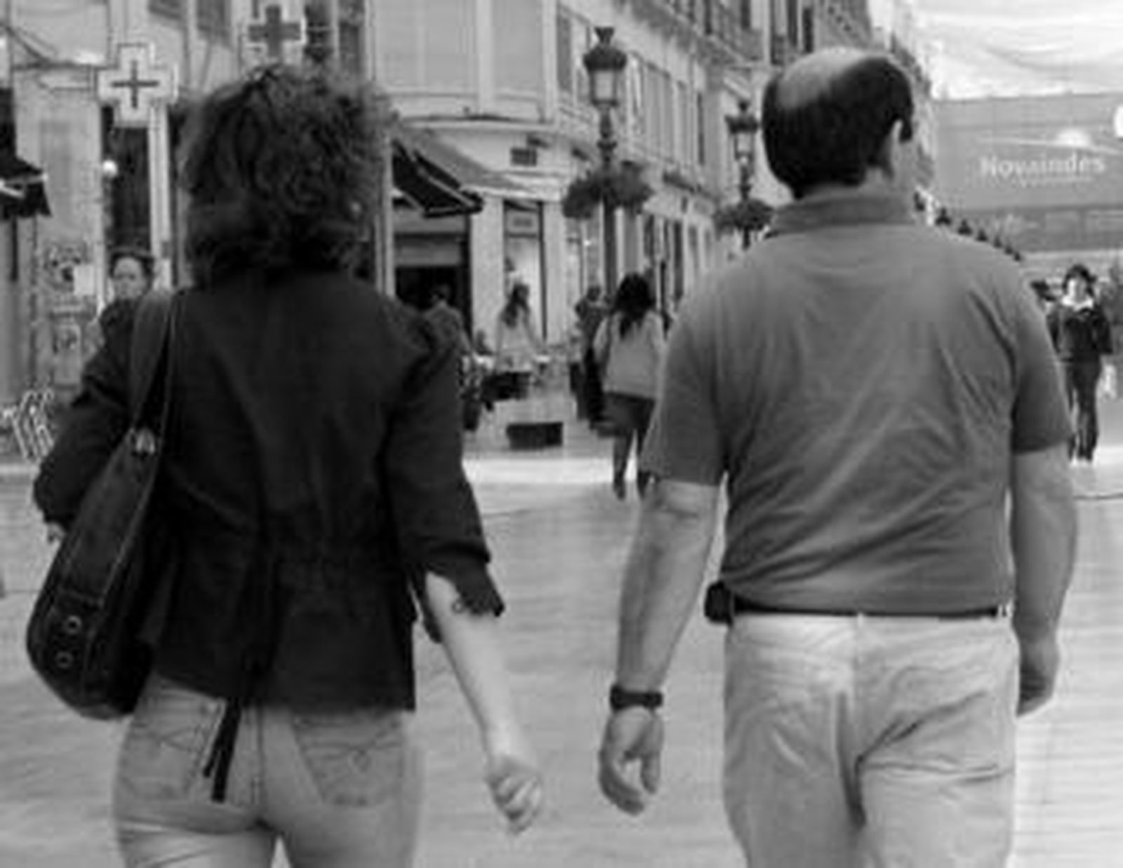 Una pareja pasea por calle Larios; cada uno mira hacia un lado.