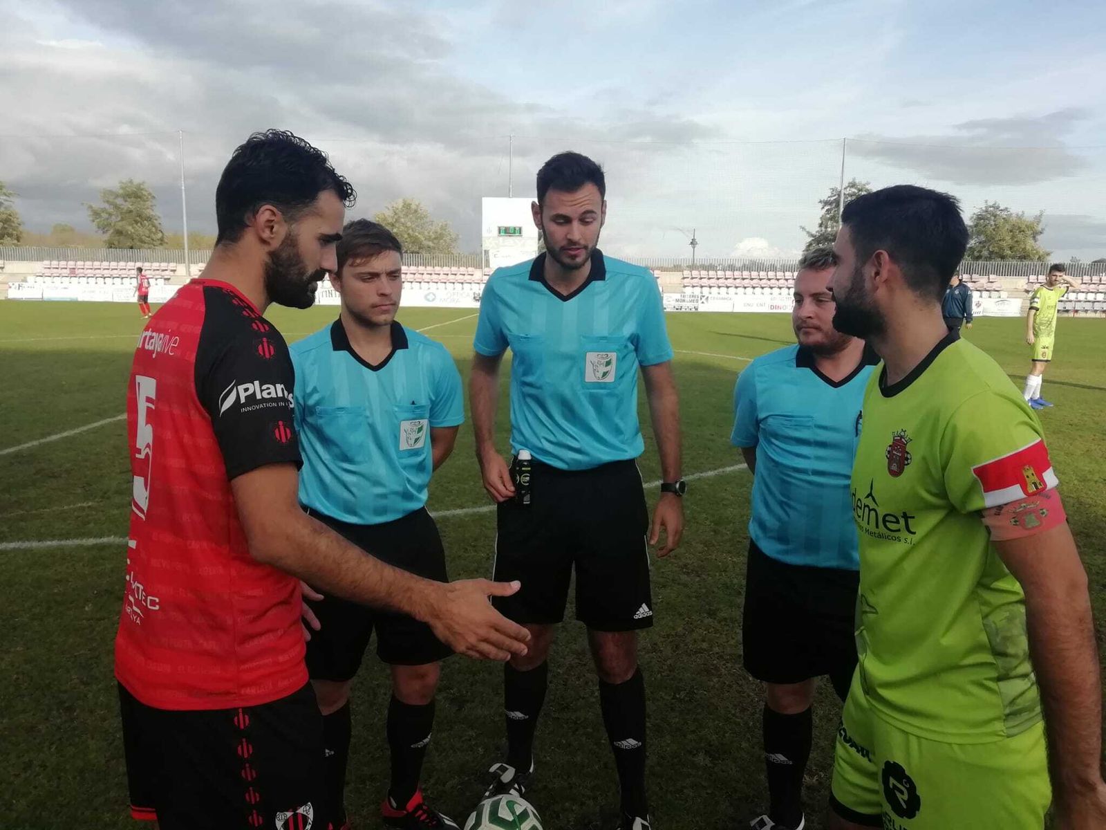 Los capitanes de ambos equipos se saludan en presencia del trío arbitral.